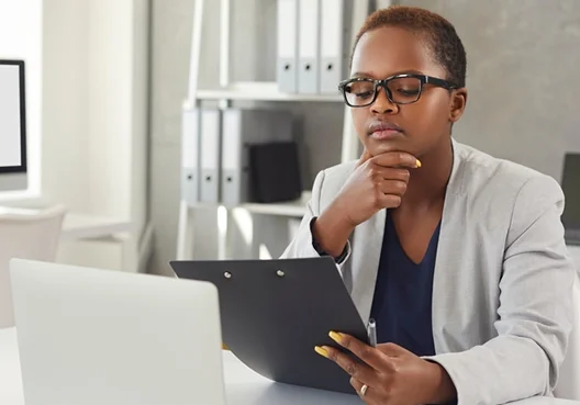 An insurance broker wearing a grey jacket holds a short-term insurance policy file in one hand.