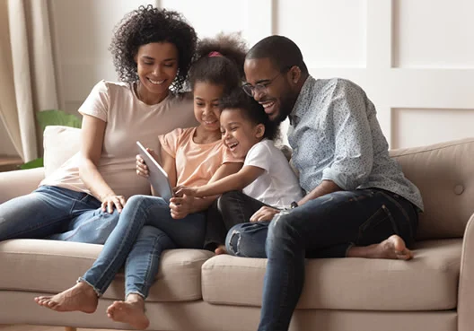 A South African family of four sitting on a couch together.