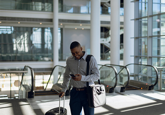 A young professional uses his phone at the airport before embarking on his business trip.