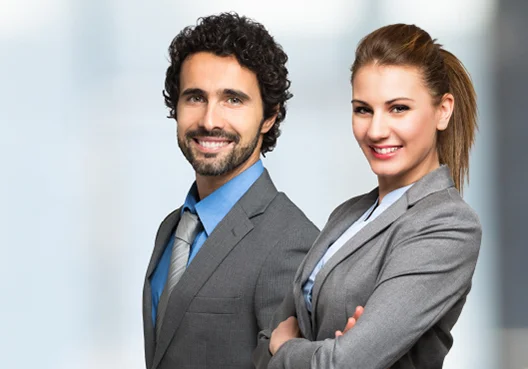 Two Corporate Property insurance specialists wearing grey suits stand next to each other. 