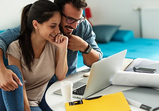 A South African couple research saving and investment products online using a laptop.