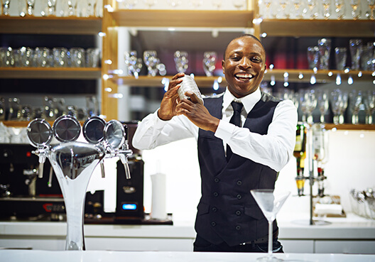 The owner of a bar prepares drinks for a group of customers. 