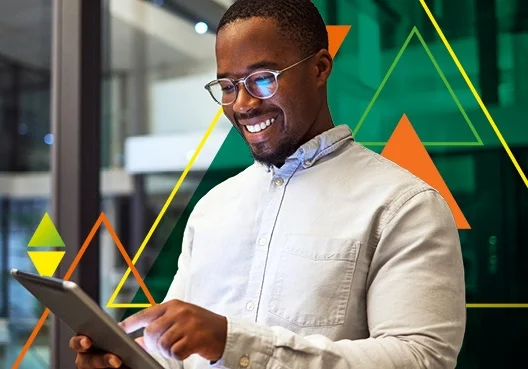 A man wearing glasses and an off white jacket uses a tablet. 