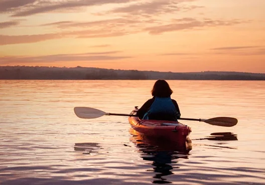 A woman shelters under a gray umbrella outside in the rain. 