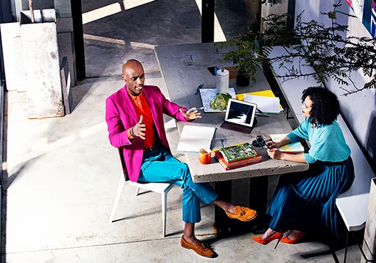 Colleauges discussing business over coffee at a table with files and laptop