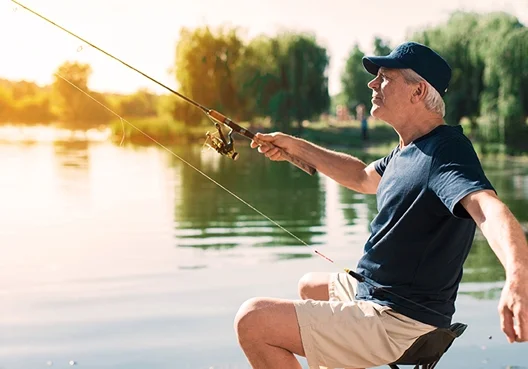 A South African mature man of retirement age fishing at a lake.