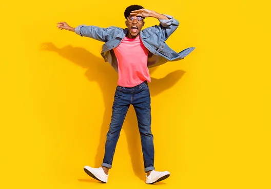 A young student wearing a pink t-shirt, dark blue jeans, and a denim jacket.