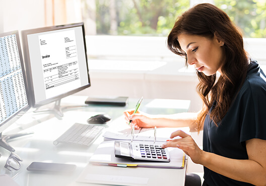 A female accountant uses a calculator at her desk. 
