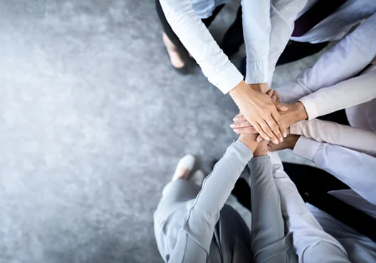 A group of insurance specialists put their hands together while standing in a circle. 