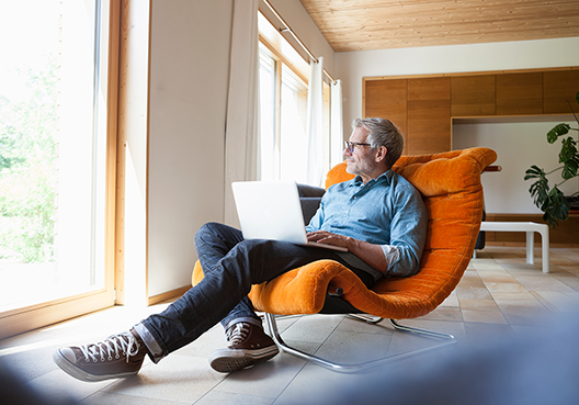 man sitting on chair with a laptop on his lap