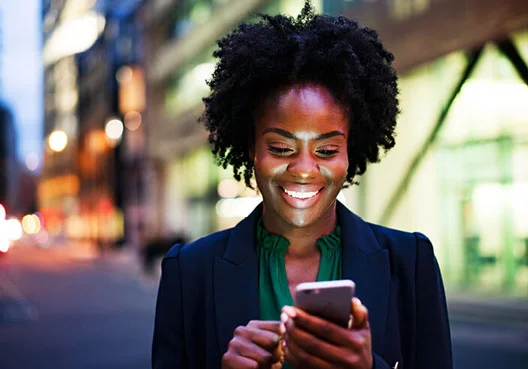 Smoothed Bonus Fund - get in touch Young woman looking at her mobile while walking down the street