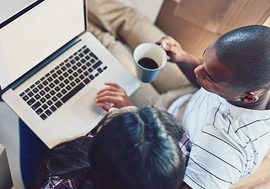 A couple go online on a laptop to give their short-term insurance company positive feedback.