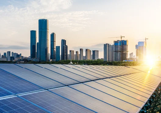 Rows of solar power panels line a rooftop in a city.