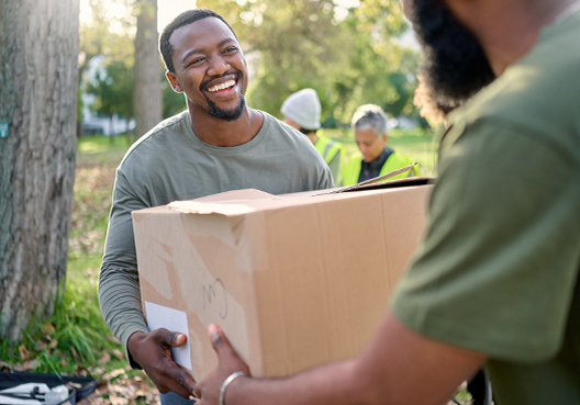 A man accepts a box of donations for communities in need. 
