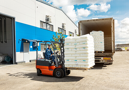 A warehouse employee transports products using a forklift. 