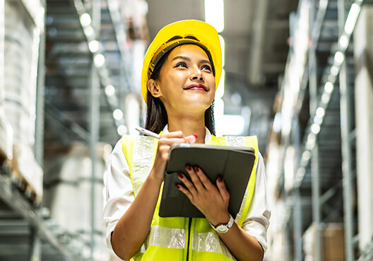 A female safety inspector wearing a yellow hardhat visits a factory.