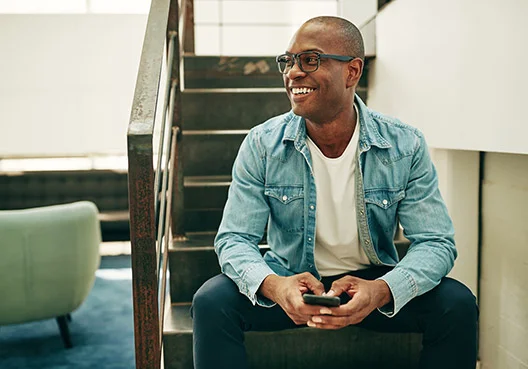 A South African professional sites on a stair while he looks at the Old Mutual website on his cellphone.