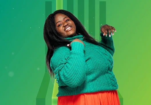 A young woman smiles after applying for a graduate programme. A young woman wearing a green polo neck jersey and orange skirt smiles.