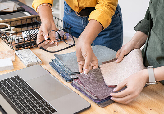 Two young fashion designers decide on which fabric samples to use for their new clothing line. 
