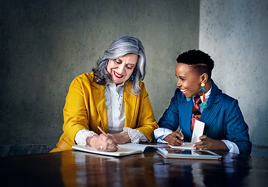 Two women at a table in a business setting laughing