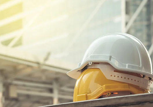 A stack of white and yellow hardhats at a construction site.
