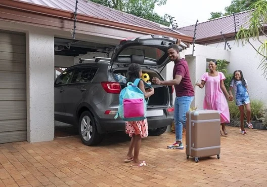 A family prepares for their holiday with a car packed and covered by short-term insurance.