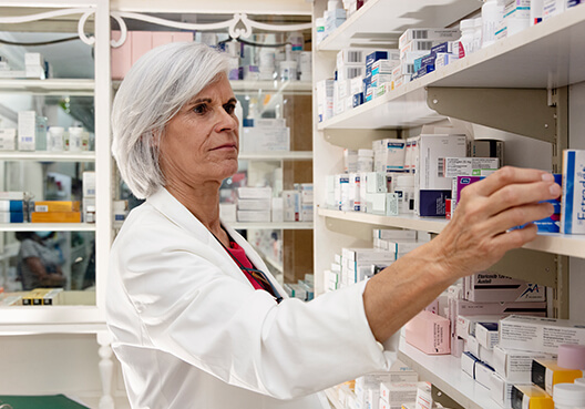 A pharmacist takes medication off the shelf at the pharmacy she owns and runs. 