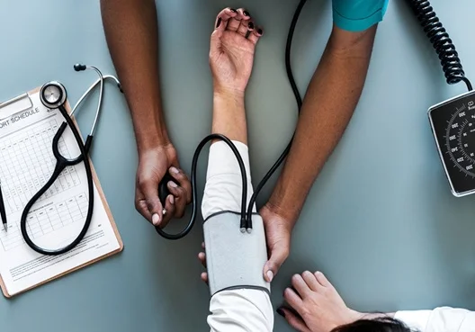 A woman has her blood pressure and heart rate measured by a male doctor.