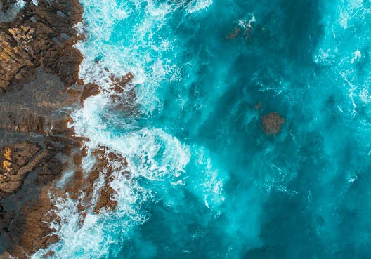 A photo of the coastline where the ocean meets the rocky shore. 