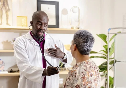 A South African doctor treats a patient at his private practice, which is covered by business insurance.