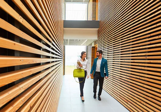 A business man and woman walking in a wood decorated passageway A business man and woman walking in a wood decorated passageway