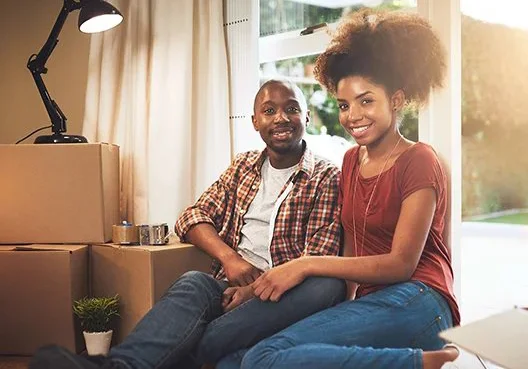 A young couple sitting on the floor smiling.