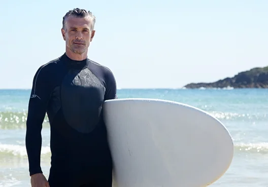 A middle-aged man takes time out to go surfing on a local beach. 
