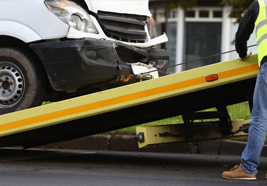 A motor vehicle used for business is involved in an accident and loaded onto a flatbed tow truck.