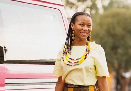 A woman accepted into the Amathuba learnership programme smiles. A young woman wearing a pale yellow t-shirt and strings of colourful beads.