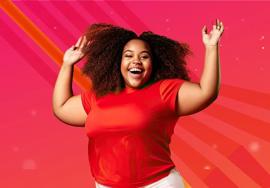 A member of the Technology Solutions team jumps with her arms up. A young woman wearing a red t-shirt and white pants throws her arms up.
