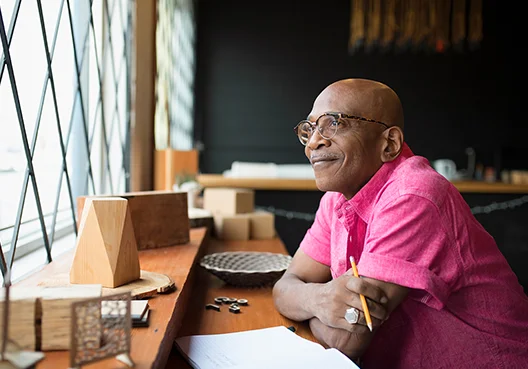A man wearing a pink shirt sits in a coffee shop reading information related to his pension fund.